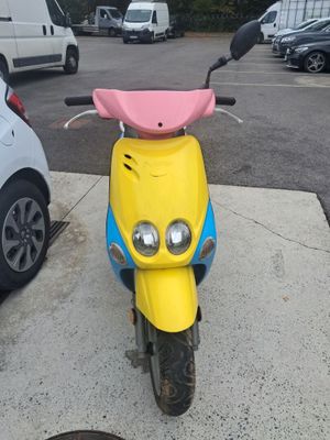 brightly colored motor scooter parked in parking lot next to parked cars