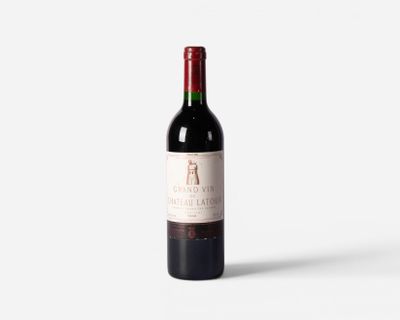 a bottle of red wine sitting on top of a white table