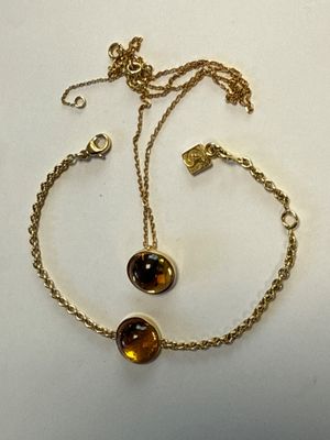 un gros plan sur un bracelet à chaîne en or orné de deux perles marron