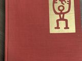 un vieux livre rouge orné d'un autocollant doré, posé sur une table en bois