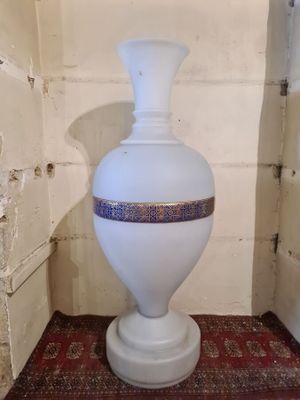 a white vase sitting on a red rug in a corner