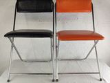 pair of black and orange folding chairs against a white wall