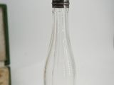 a small glass bottle with a silver top next to an open box