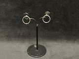 pair of silver hoop earrings on a black stand against a black background