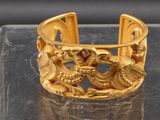 un bracelet en or orné de deux oiseaux, posé sur une table