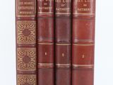 three old books sitting on top of each other on a white surface