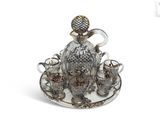 a silver plate with a glass bird and teacups on it