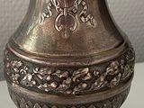 a silver vase sitting on a table with a tag on it