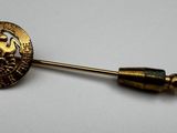 a gold pin with a face on it on a white surface