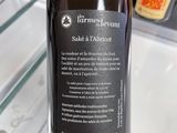someone is holding a bottle of wine in front of a refrigerator