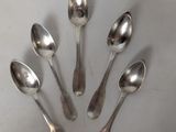 six silver spoons are arranged in a circle on a white surface