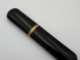 un gros plan d'un stylo noir orné d'une bague dorée