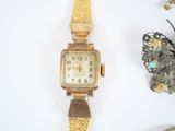 a gold watch sitting next to a butterfly on a white surface