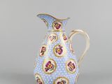 a blue and white pitcher with gold trimming and flowers on it