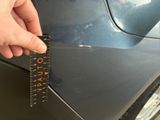 a person holding a ruler that is on the side of a car