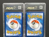 two packs of pokemon trading cards in plastic cases on a black surface