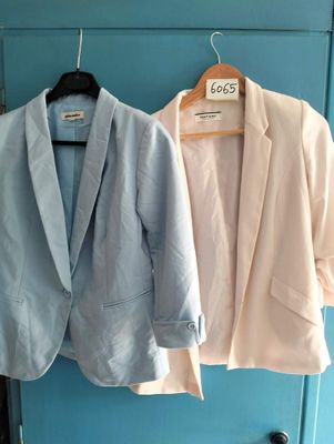 two jackets hanging on a clothes rack next to each other