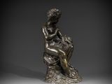 a bronze statue of a woman sitting on a rock