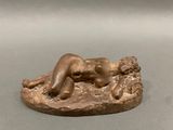 statue en bronze représentant une femme allongée sur un rocher, les jambes croisées