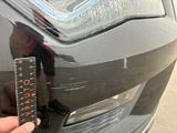 a person holding a ruler next to the front of a car