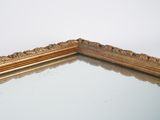 a mirror with a gold frame on a white wall