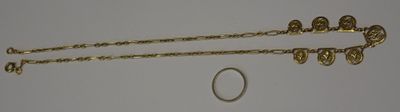 two gold chains and a ring on a white surface
