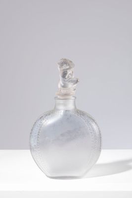 une bouteille en verre transparent avec un bouchon argenté, posée sur une table