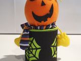 a stuffed pumpkin in a black shirt and a green hat