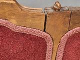 a close up of a red chair with a wooden frame