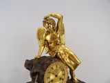 a gold statue of an angel sitting on top of a clock