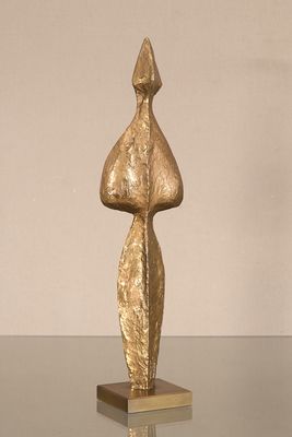 une sculpture en or posée sur une table en verre, avec un mur blanc en arrière-plan