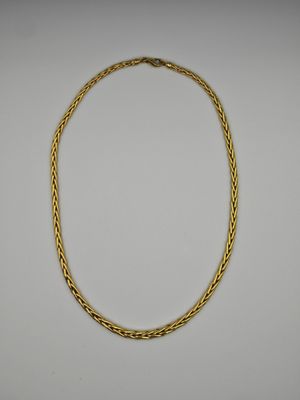 un collier en or avec un motif tressé sur fond blanc