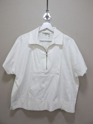 the white shirt is hanging on a hanger on the wall