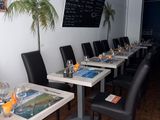Ce restaurant compte de nombreuses tables et chaises, et les menus sont affichés au mur.