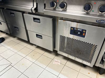 Plusieurs appareils électroménagers en acier inoxydable sont alignés sur un sol carrelé