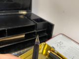 a person holding a pen in their hand near a box of pens