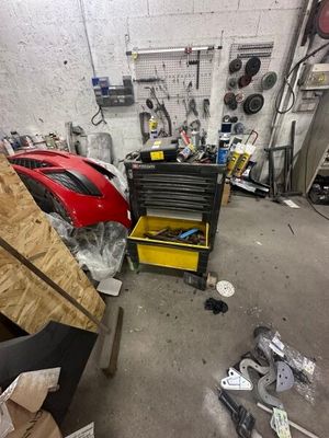 un garage rempli d'outils et d'une voiture de sport rouge