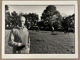 photographie en noir et blanc d'un homme debout devant un troupeau de chevaux