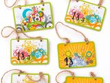 quatre étiquettes aux motifs variés suspendues à des ficelles sur une surface blanche