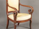 une chaise en bois avec une assise et des accoudoirs rembourrés à rayures