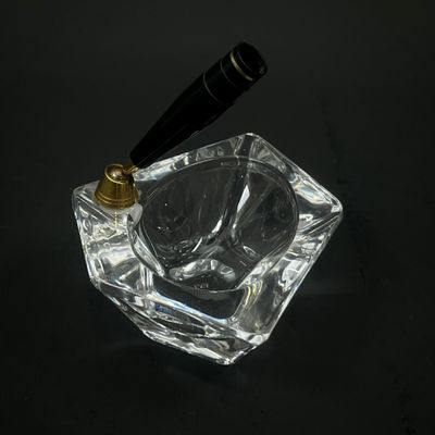un cendrier en verre muni d'une poignée noire, posé sur une table noire
