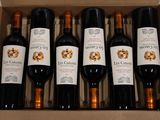 six bottles of red wine in a cardboard box on a table