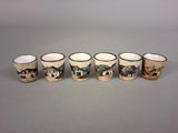 four cups with different designs are lined up on a gray surface