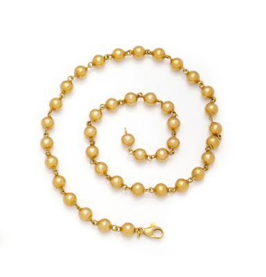 a close up of a gold beaded necklace and bracelet on a white background
