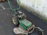 a green lawn mower sitting on the side of the road