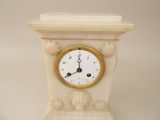 a white clock with a gold face on a white table