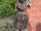a wooden statue of a woman standing on a brick walkway