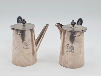 paire de cafetières plaquées argent avec des anses, posées sur un support blanc