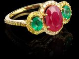 un gros plan d'une bague en or sertie d'un rubis, d'une émeraude et de diamants jaunes