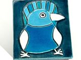 a blue bird sitting on top of a blue tile